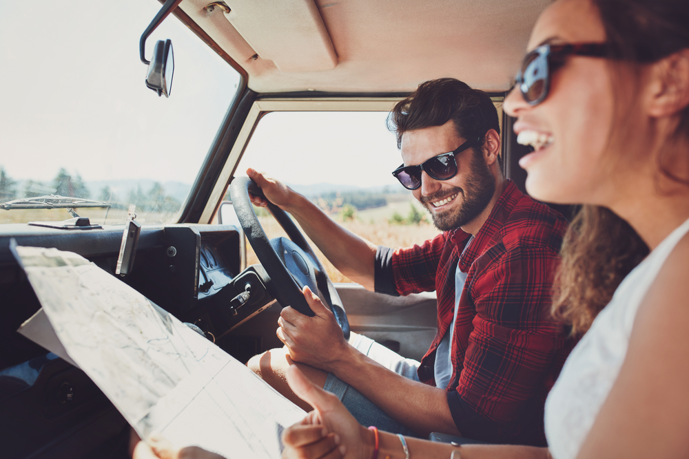 Shutterstock _ ID: 394099399 Happy young couple with a map in the car. Smiling man and woman using map on roadtrip.