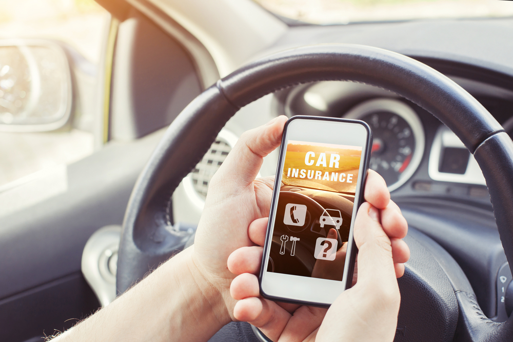Shutterstock_703768939 car insurance concept, driver reading website on smartphone