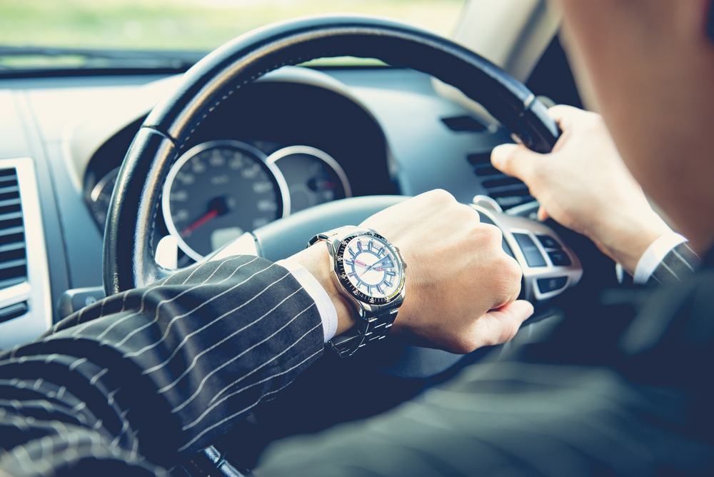 Shutterstock_368989106 Man driving a car and looking at watch ,business concept ,vintage tone